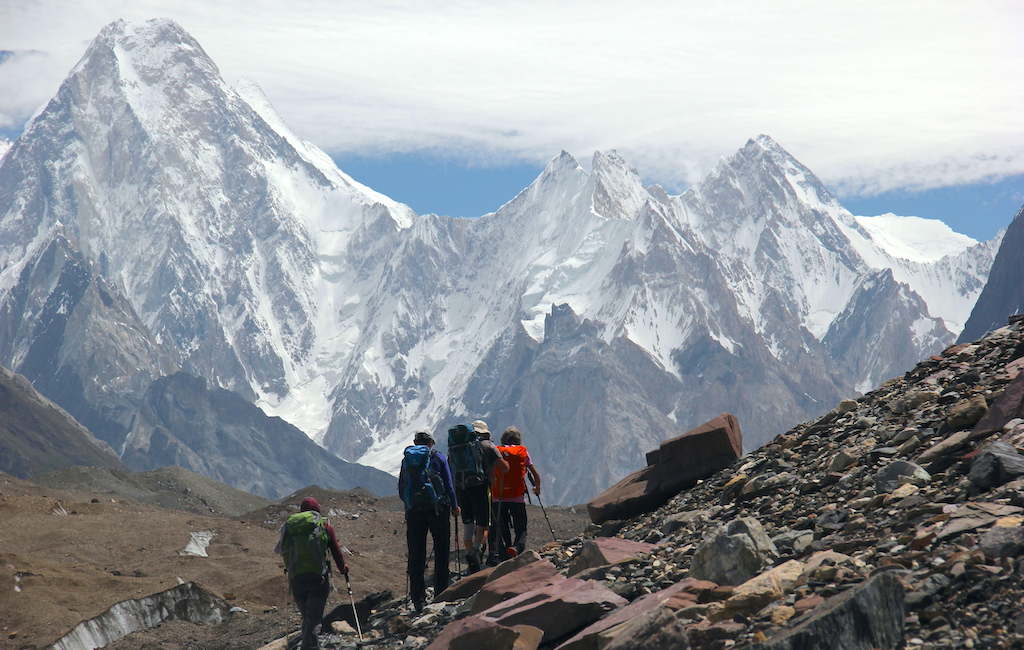 A group of hikers trekking on the Baltoro Glacier, with snow-capped mountains as an impressive backdrop.