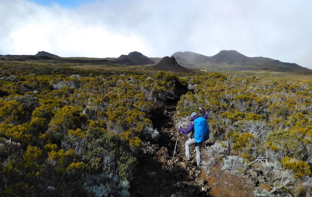 A hiker walking with a backpack while trekking on Reunion Island.